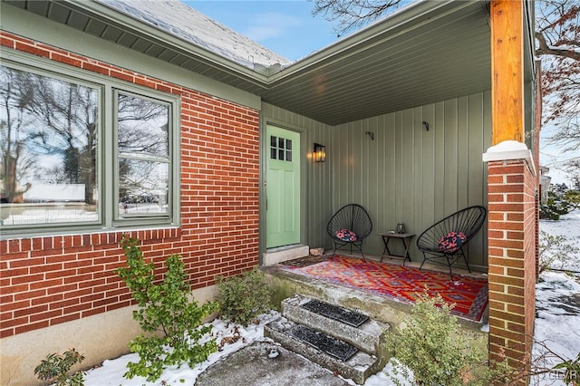 snow covered property entrance with a porch