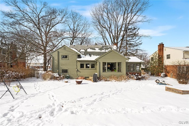 snow covered rear of property with a sunroom