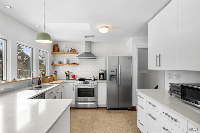 kitchen with wall chimney exhaust hood, white cabinetry, stainless steel appliances, and sink