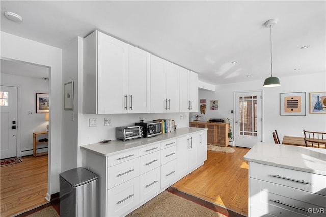 kitchen featuring hanging light fixtures, a baseboard radiator, white cabinets, and light hardwood / wood-style floors