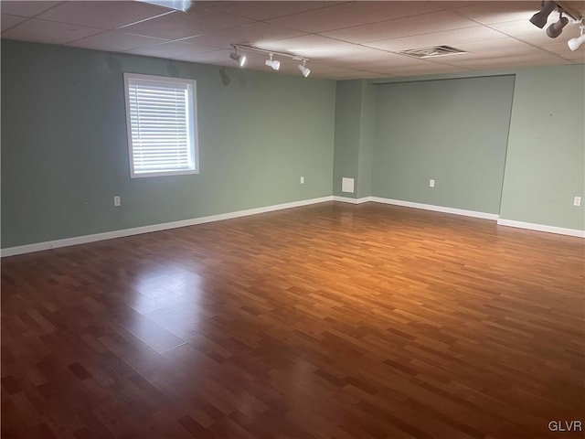 spare room with dark wood-type flooring, track lighting, and a drop ceiling