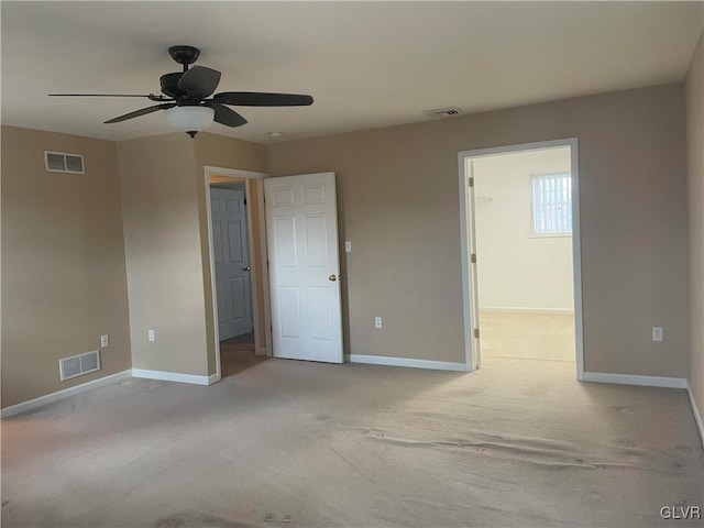 unfurnished bedroom with light carpet, a walk in closet, and ceiling fan