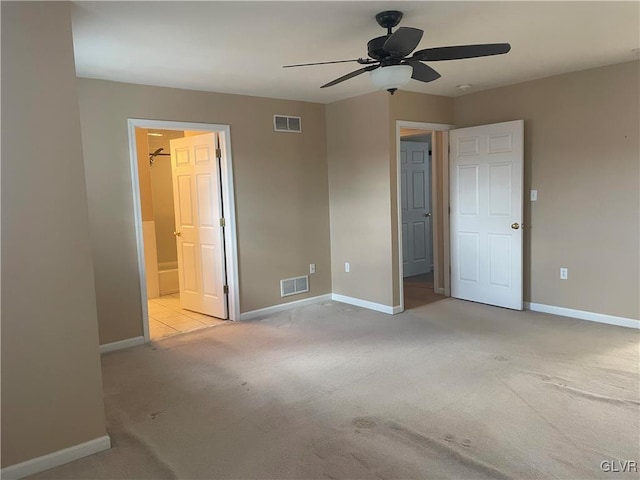 unfurnished bedroom featuring ensuite bathroom, light colored carpet, and ceiling fan