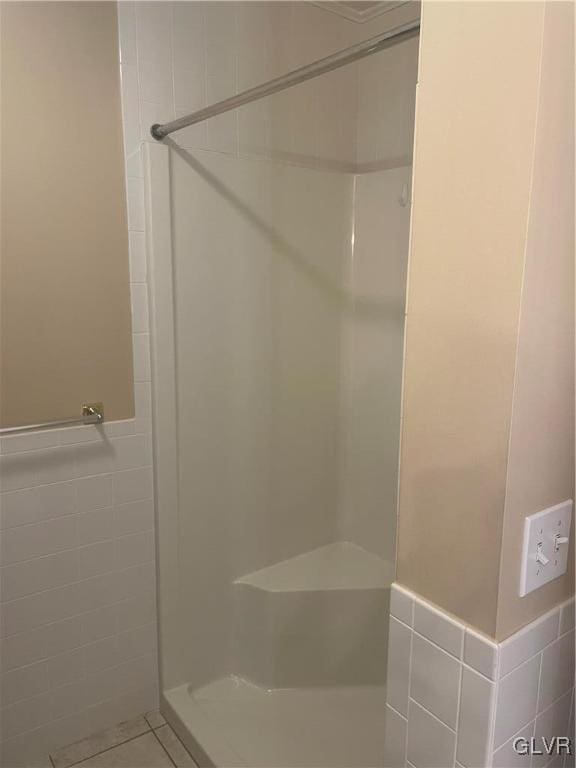 bathroom featuring tile patterned flooring, tile walls, and walk in shower