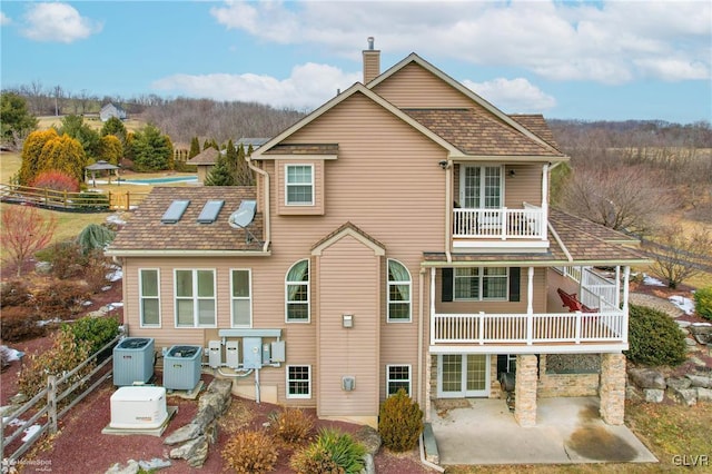 rear view of property with central AC unit, a patio, and a balcony