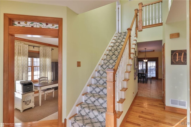 stairs with a wealth of natural light and hardwood / wood-style floors