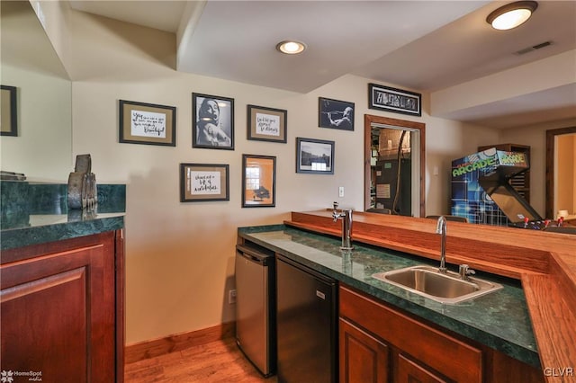 bar featuring sink, dishwashing machine, and light wood-type flooring