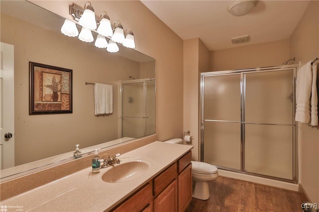 bathroom with hardwood / wood-style flooring, vanity, toilet, and a shower with door