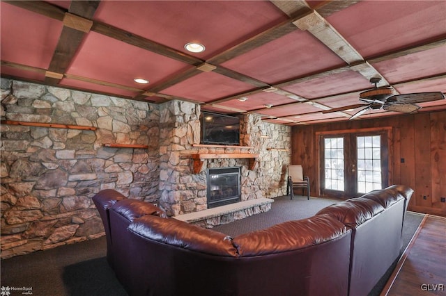 unfurnished living room with coffered ceiling, a stone fireplace, wood walls, wood-type flooring, and beamed ceiling