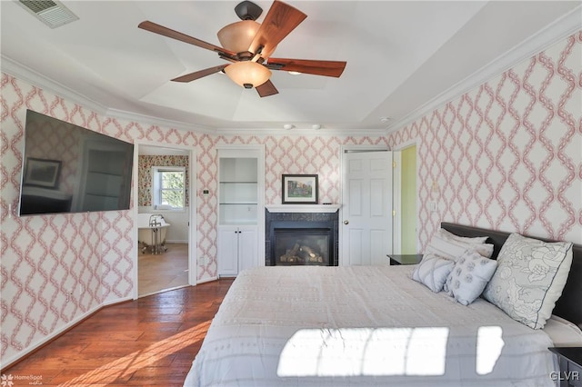 bedroom with a tray ceiling, dark wood-type flooring, ornamental molding, and ceiling fan