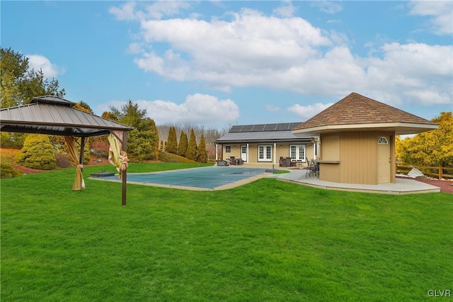 rear view of house with a gazebo, a lawn, a patio area, and solar panels