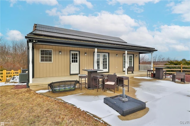 rear view of house with solar panels, central AC, and french doors