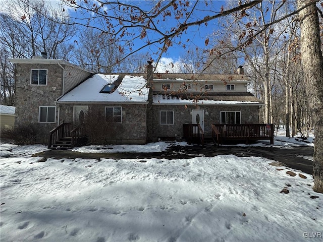 snow covered back of property featuring a wooden deck