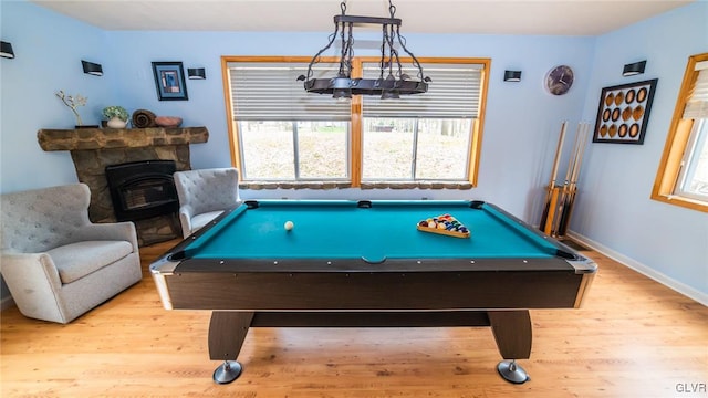 playroom featuring a stone fireplace and light hardwood / wood-style flooring