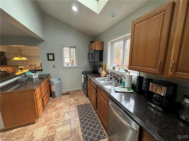 kitchen featuring stainless steel appliances, lofted ceiling with skylight, sink, and a wealth of natural light