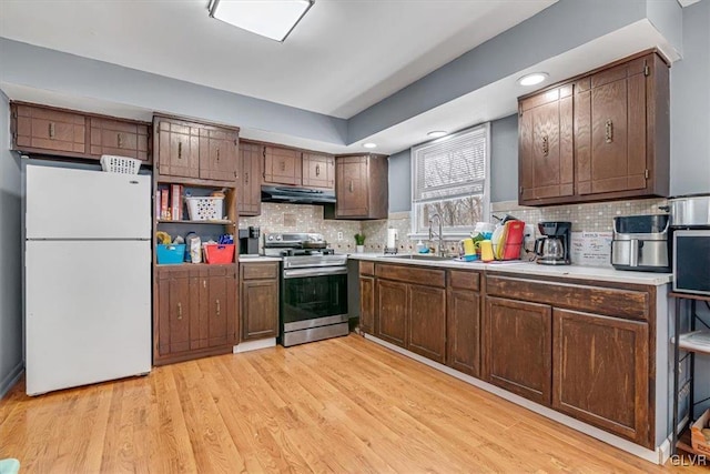 kitchen featuring sink, stainless steel electric range oven, light wood-type flooring, white refrigerator, and backsplash