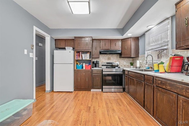 kitchen with white refrigerator, sink, decorative backsplash, and electric range