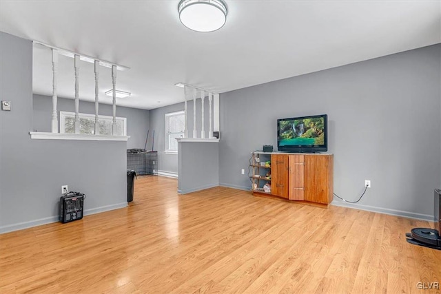 unfurnished living room featuring light hardwood / wood-style flooring, a baseboard radiator, and track lighting