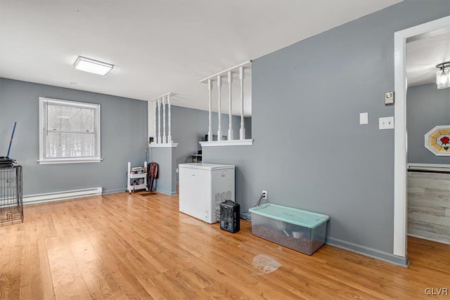 clothes washing area featuring baseboard heating and light hardwood / wood-style floors