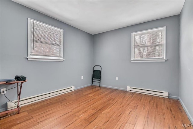 empty room with a baseboard radiator and light hardwood / wood-style flooring