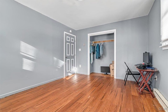 bedroom featuring light wood-type flooring, a closet, and a baseboard heating unit