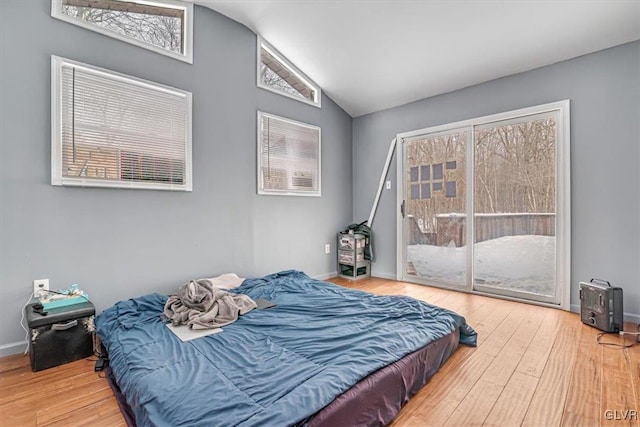 bedroom featuring access to exterior, vaulted ceiling, and wood-type flooring