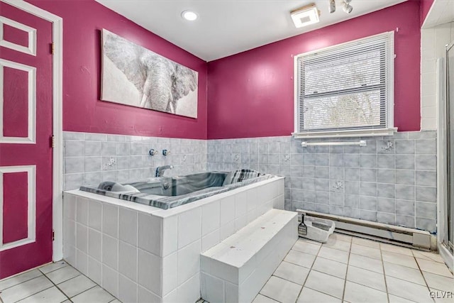 bathroom with tile patterned flooring, a baseboard radiator, a relaxing tiled tub, and tile walls