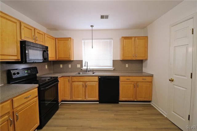 kitchen featuring tasteful backsplash, sink, hanging light fixtures, black appliances, and light hardwood / wood-style flooring