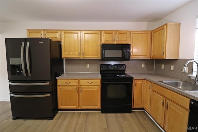 kitchen with sink, backsplash, light hardwood / wood-style floors, black appliances, and light brown cabinets