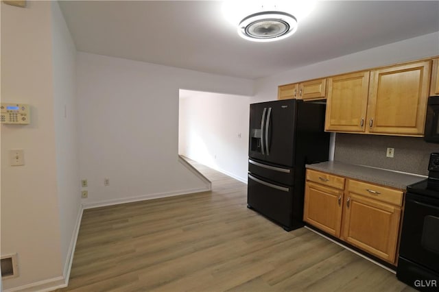 kitchen with light hardwood / wood-style flooring and black appliances