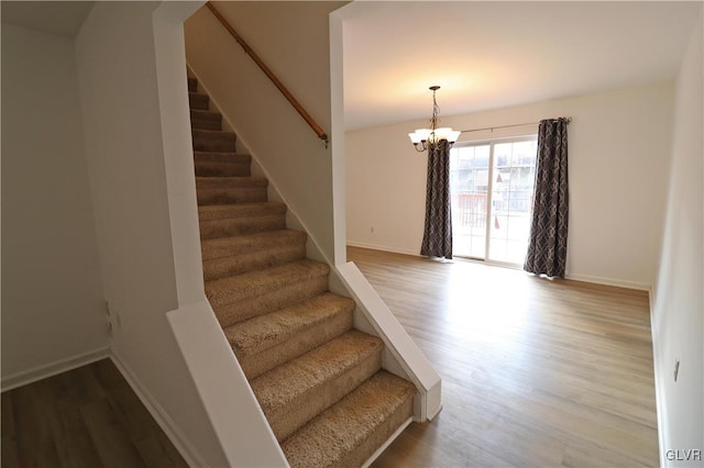 stairs with hardwood / wood-style floors and a chandelier