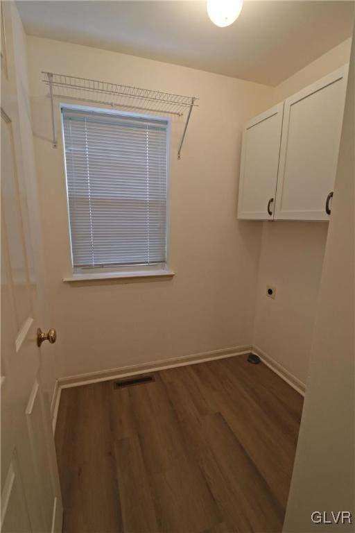 washroom featuring electric dryer hookup, wood-type flooring, and cabinets