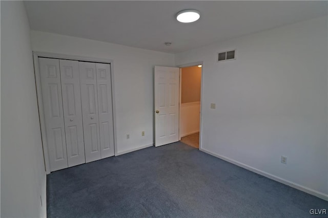 unfurnished bedroom featuring dark carpet and a closet