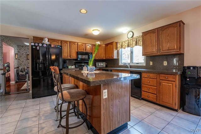 kitchen featuring light tile patterned flooring, sink, a center island, decorative backsplash, and black appliances