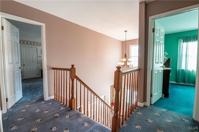 stairway with a notable chandelier, a healthy amount of sunlight, and carpet