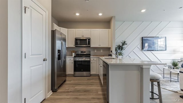 kitchen featuring white cabinetry, stainless steel appliances, kitchen peninsula, and a breakfast bar area