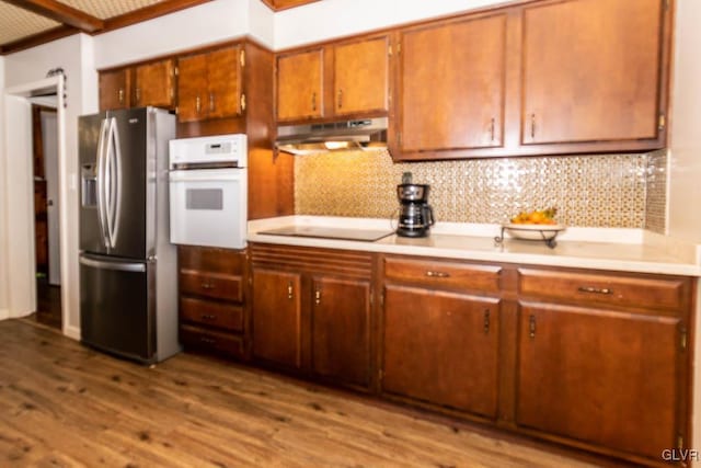 kitchen featuring stainless steel fridge, tasteful backsplash, black electric stovetop, light hardwood / wood-style floors, and oven