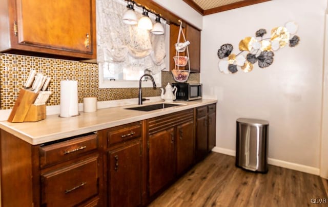 kitchen with sink, hanging light fixtures, ornamental molding, dark hardwood / wood-style floors, and backsplash