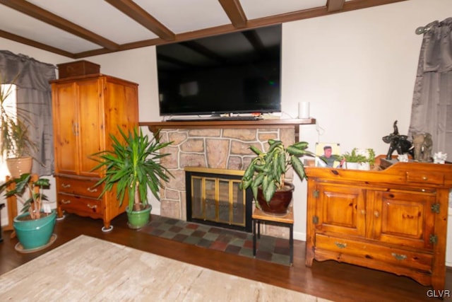 living room with beam ceiling, a stone fireplace, and dark wood-type flooring