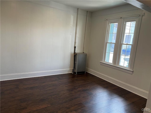 unfurnished room with dark hardwood / wood-style flooring and radiator