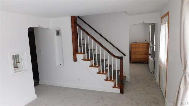 stairs featuring radiator and carpet floors