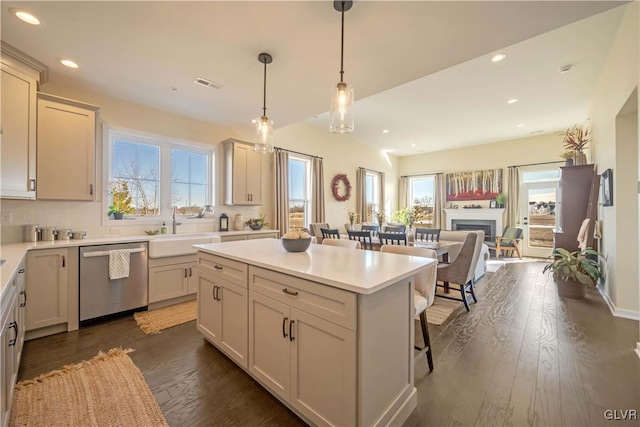 kitchen with sink, a breakfast bar area, dishwasher, a kitchen island, and pendant lighting