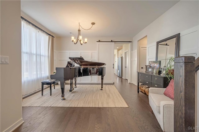 misc room with a notable chandelier, a barn door, and light wood-type flooring