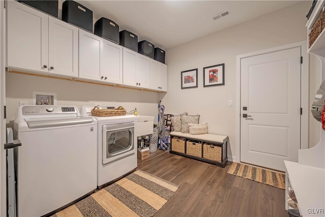 clothes washing area with cabinets, dark wood-type flooring, and washer and dryer