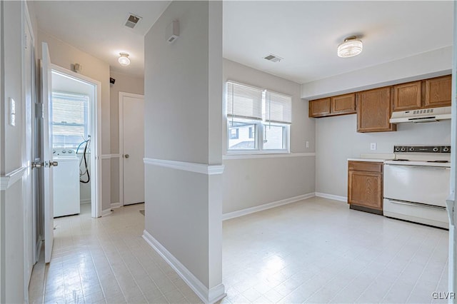 kitchen featuring white electric stove, a healthy amount of sunlight, and washer / clothes dryer