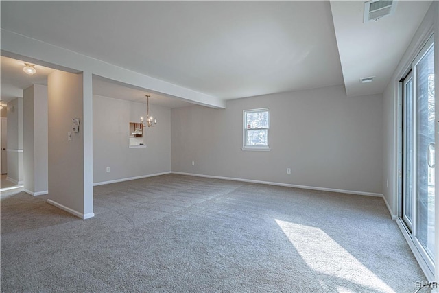 carpeted empty room featuring an inviting chandelier