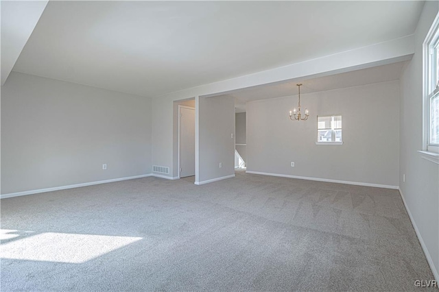 empty room with carpet flooring and a chandelier