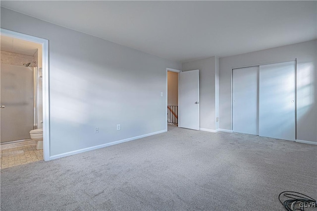 unfurnished bedroom featuring ensuite bath, carpet floors, and a closet