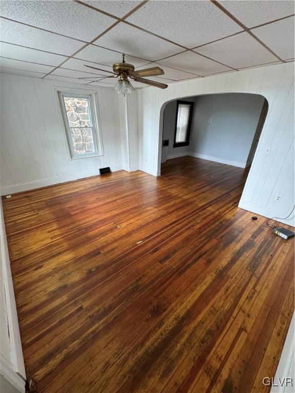 unfurnished living room featuring ceiling fan, dark hardwood / wood-style floors, and a drop ceiling