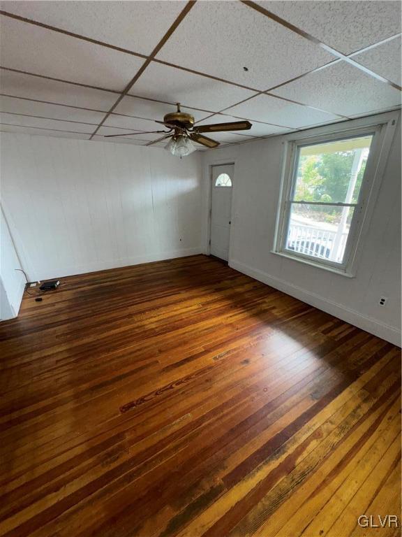 unfurnished room with a drop ceiling, dark wood-type flooring, and ceiling fan